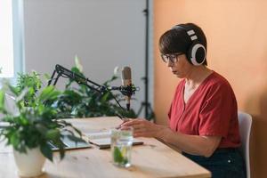 Middle-aged woman radio host making podcast recording for online show - broadcast and dj concept photo