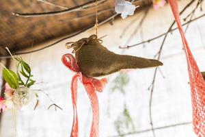 Hanging ribbon and bird shape linen fabric and flower clear glass vase on background , artificial flowers hang in a wedding party or interior. Decoration indoors photo
