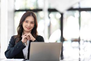 Asian Business woman using calculator and laptop for doing math finance on an office desk, tax, report, accounting, statistics, and analytical research concept photo