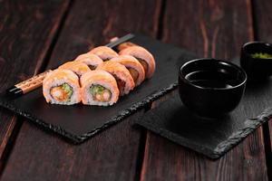 Sushi roll philadelphia with crab and cucumber and cream cheese, caviar on black background close-up. Sushi menu. Japanese food concept photo