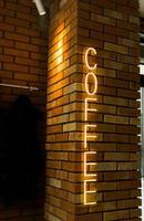 Coffee neon sign emblem in neon style on brick wall background. Coffee shop photo