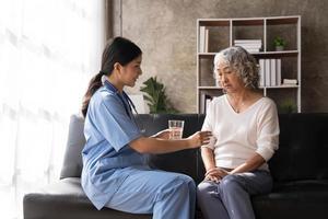Healthcare worker or nurse caregiver giving pills, showing a prescription drug to senior woman. Elderly healthcare concept