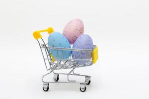 Colorful easter eggs in shopping cart on grey background. Copy space. photo