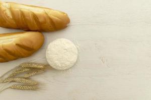 Homemade fresh bread with wheat ear on white wood table. photo