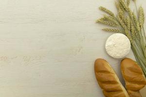 Homemade fresh bread with wheat ear on white wood table. photo