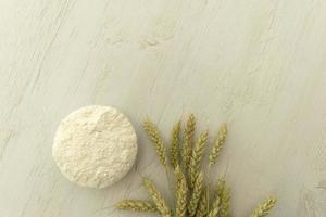 Bunch wheat ear and flour on white wood table. photo