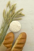 pan fresco casero con espiga de trigo sobre mesa de madera blanca. foto
