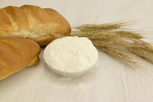 Homemade fresh bread with wheat ear on white wood table. photo