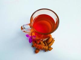 Close-up of turmeric pieces on a decorated table cloth, traditional indonesian Jamu drink in a bottle and in a cup. photo