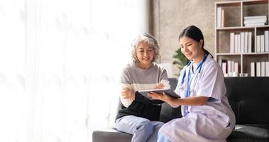 Young caregiver helping senior woman walking. Nurse assisting her old woman patient at nursing home. Senior woman with walking stick being helped by nurse at home. photo