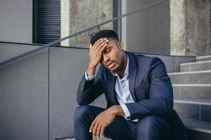 african businessman sitting frustrated on the stairs depressed by the results of his work photo