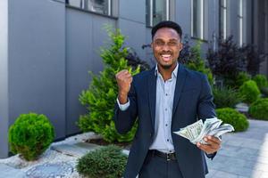 Happy successful African American businessman counts, waves, throws, show off photo