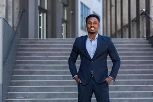 Successful happy businessman outside office posing and looking at camera african american photo