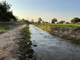 flujo de agua de riego desde la tubería hasta el canal para campos agrícolas foto