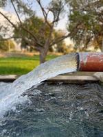 flujo de agua de riego desde la tubería hasta el canal para campos agrícolas foto