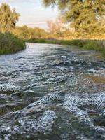 flujo de agua de riego desde la tubería hasta el canal para campos agrícolas foto