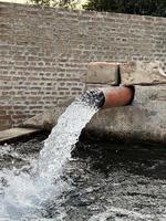 flujo de agua de riego desde la tubería hasta el canal para campos agrícolas foto