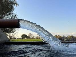 flujo de agua de riego desde la tubería hasta el canal para campos agrícolas foto