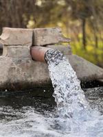 flujo de agua de riego desde la tubería hasta el canal para campos agrícolas foto