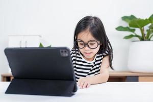 Asian child girl student wow excited on video call learning to studying online class or person learn from home school with tablet photo