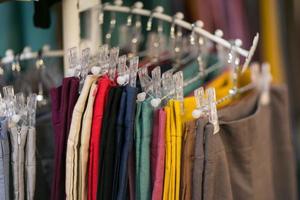 Clothes that are arranged on shelves and hangers photo