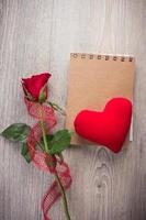 Red rose and note book on old wood background photo