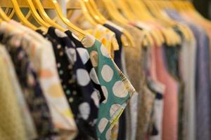 Clothes that are arranged on shelves and hangers photo