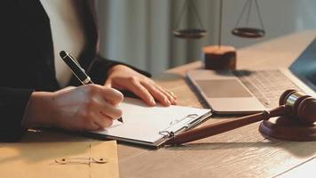 Business and lawyers discussing contract papers with brass scale on desk in office. Law, legal services, advice, justice and law concept picture with film grain effect video