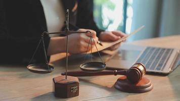 Business and lawyers discussing contract papers with brass scale on desk in office. Law, legal services, advice, justice and law concept picture with film grain effect video