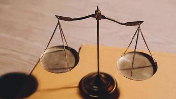 Business and lawyers discussing contract papers with brass scale on desk in office. Law, legal services, advice, justice and law concept picture with film grain effect video