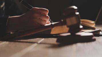 Business and lawyers discussing contract papers with brass scale on desk in office. Law, legal services, advice, justice and law concept picture with film grain effect video