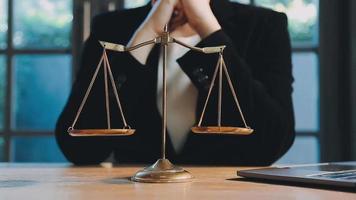 Business and lawyers discussing contract papers with brass scale on desk in office. Law, legal services, advice, justice and law concept picture with film grain effect video