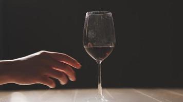 impostato di mani Tenere rosso vino bicchiere isolato su nero sfondo. video