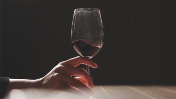 Set of hands holding red wine glass isolated on black background. video