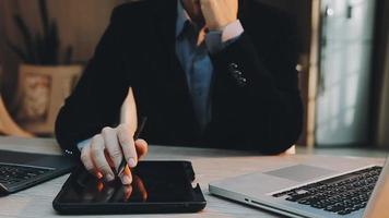 Image of two young businessmen using touchpad at meeting video