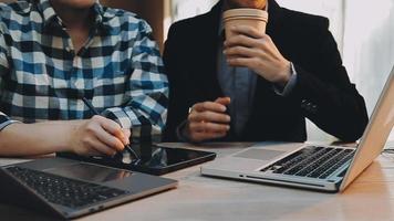 Image of two young businessmen using touchpad at meeting video