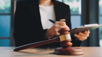 Business and lawyers discussing contract papers with brass scale on desk in office. Law, legal services, advice, justice and law concept picture with film grain effect video