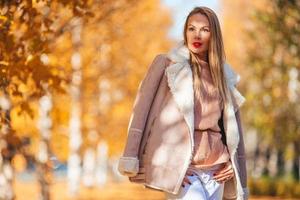 concepto de otoño - mujer hermosa en el parque de otoño bajo el follaje de otoño foto