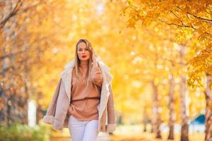 concepto de otoño - mujer hermosa en el parque de otoño bajo el follaje de otoño foto