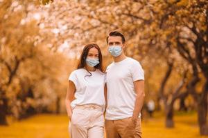Adorable family in blooming cherry garden in masks photo
