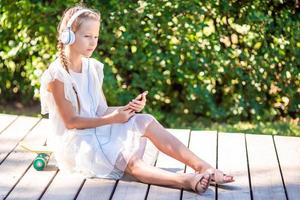 Little adorable girl listening music in the park photo