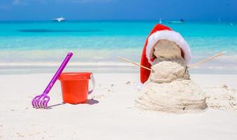Sandy snowman with red Santa Hat and beach toys photo