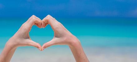 Close up of heart made by hands background turquoise ocean photo
