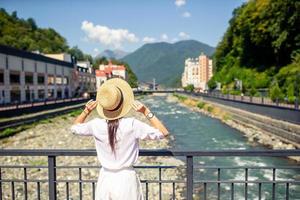 chica feliz con sombrero en el terraplén de un río de montaña en una ciudad europea. foto