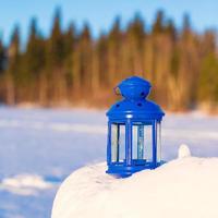 linterna azul con una vela en la nieve blanca al aire libre foto