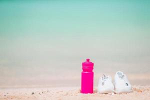 Sport shoes and bottle on white sandy beach photo