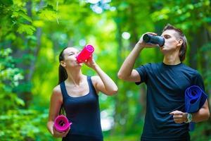 Jogging active couple have a rest with mat and bottle of water outdoors in forest photo