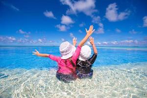 Adorable little girls playing in outdoor swimming pool photo