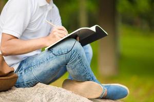 Close up of hands of boy studying for college exam in park outside photo