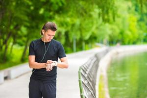 Runner looking at smart watch heart rate monitor having break while running photo